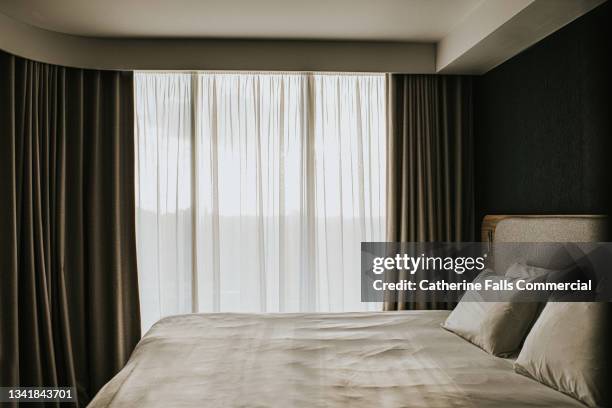 a simple, neat and sparse bedroom in an apartment or hotel room. - motel stockfoto's en -beelden