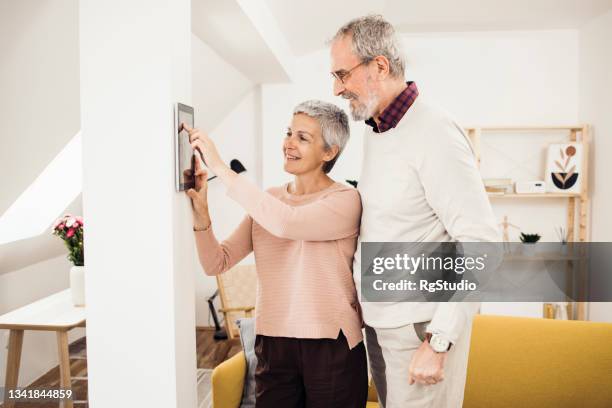 happy senior man and woman using a smart system at their house - smart house stock pictures, royalty-free photos & images