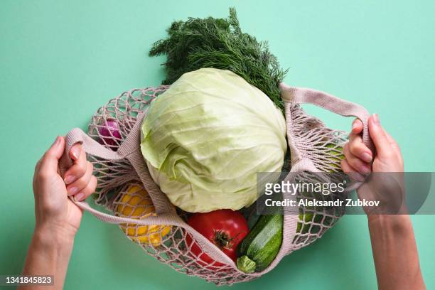 fresh ripe fruits or vegetables in a reusable shopping bag. a string bag made of recycled materials in the hands of a girl or woman, on a background or table. vegetarianism, veganism, raw food. cultivation of organic farm eco-products. no plastic and gmos - plastfritt bildbanksfoton och bilder