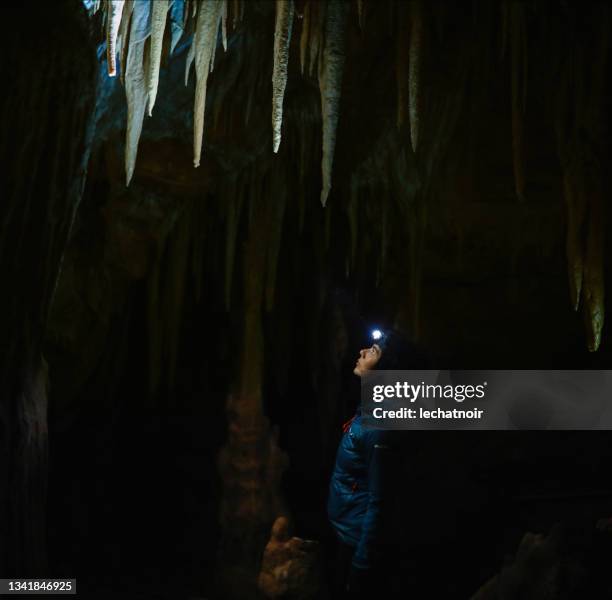 tourist woman walking through the underground cave - speleology stock pictures, royalty-free photos & images