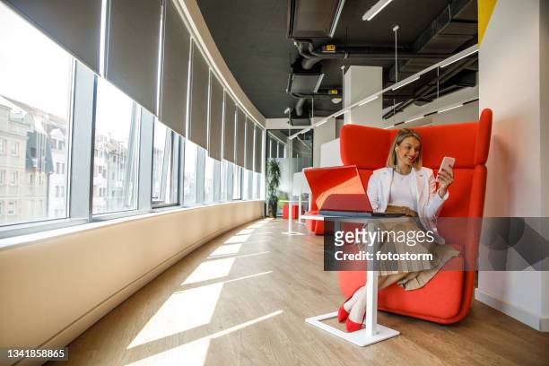 young enterprenuer having a video call in coworking office space - red office chair stock pictures, royalty-free photos & images