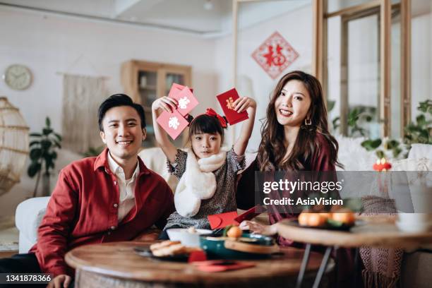 fröhliche asiatische familie hält rote umhüllungen (lai sehen) und feiert chinesisches neujahr zusammen - kung hei fat choi stock-fotos und bilder