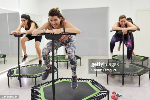 ein mid-adult-instruktor springt auf einem fitness-trampolin. - trampolin stock-fotos und bilder