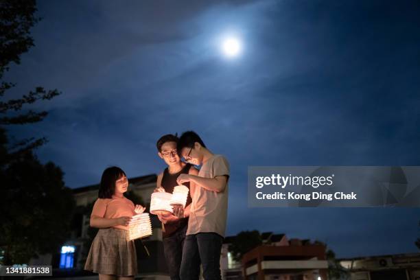 asian chinese father with children and nephew holding paper lantern, celebration mid autumn festival. - chinees lantaarnfeest stockfoto's en -beelden