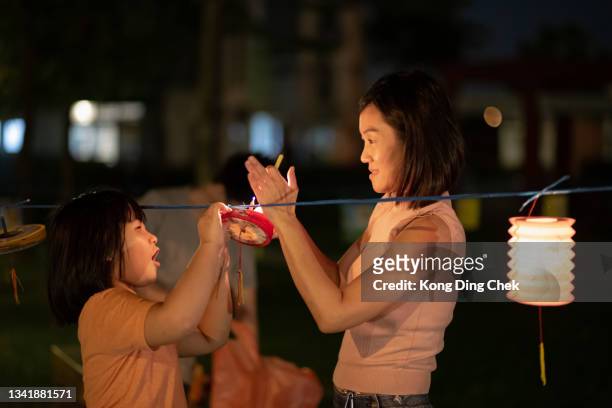 asian chinese mother and daughter light up candle in the paper lantern, celebration mid autumn festival.vvvvvvvvvvv - chinees lantaarnfeest stockfoto's en -beelden
