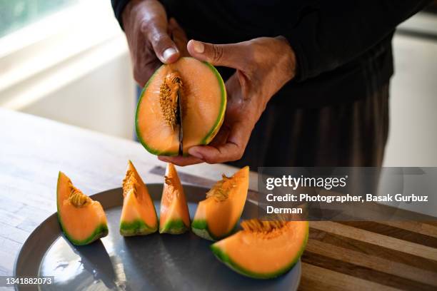 a man removing the seeds of a cantaloupe, melon. - meloen stockfoto's en -beelden