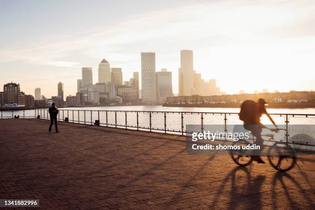 early morning commuters against canary wharf skyline - persona in secondo piano foto e immagini stock