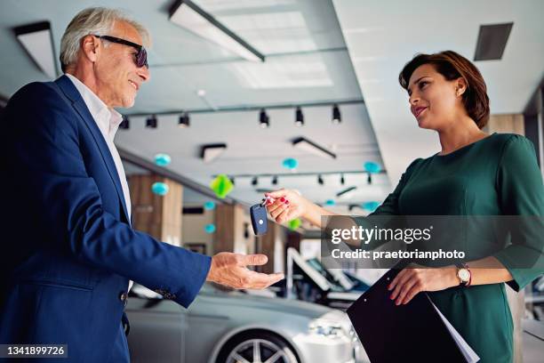 car dealer is giving car key to a customer - sports car showroom stock pictures, royalty-free photos & images