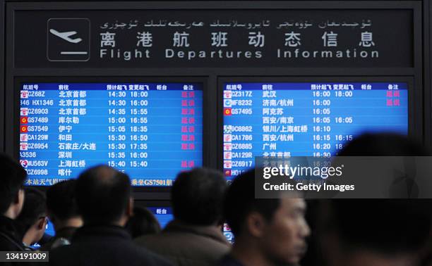 Passengers look at a departure board while stranded as heavy fog envelops Urumqi International Airport on November 27, 2011 in Urumqi, China. Dense...