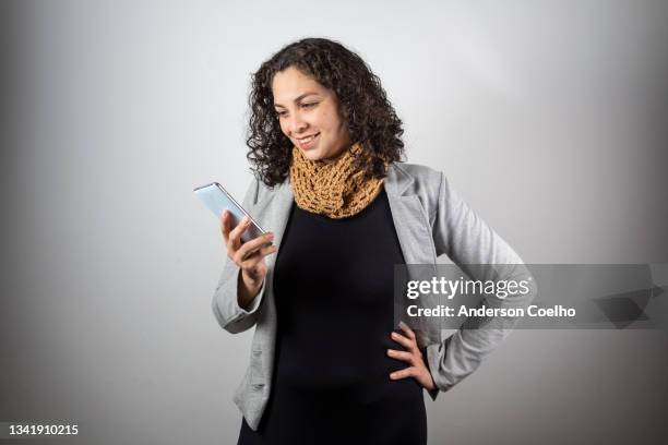 latin woman over 30 years old posing in studio with phone - woman 30 years old portrait stock pictures, royalty-free photos & images