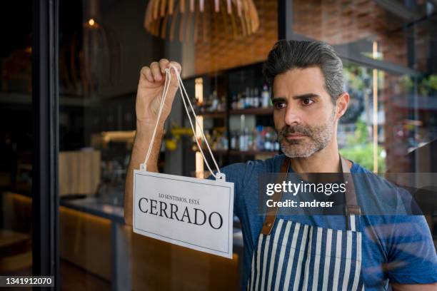 dueño de negocio colgando un letrero cerrado en español en un restaurante - bancarrota fotografías e imágenes de stock