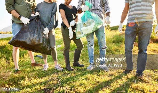 volunteers standing with bags of litter during a cleanup day by a river - close to stockfoto's en -beelden