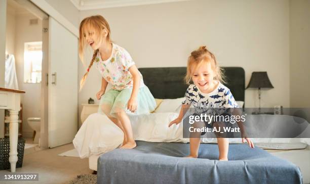deux petits frères et sœurs rieurs qui sautent sur le lit de leurs parents - jump on bed photos et images de collection