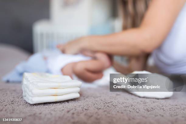 mother changing diapers to a baby - birthing stool stock pictures, royalty-free photos & images
