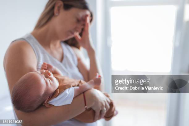 woman having headache when holding a baby - employment and labour 個照片及圖片檔