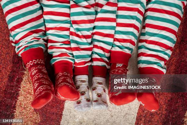 family lying on the carpet in pyjamas and christmas socks - legs in stockings stockfoto's en -beelden