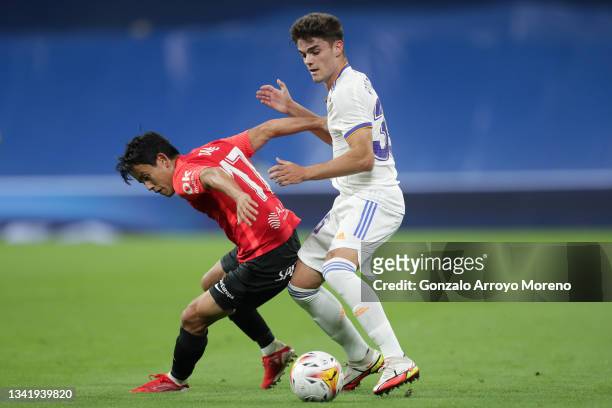 Take Kubo of RCD Mallorca competes for the ball with Miguel Gutierrez of Real Madrid CF during the La Liga Santander match between Real Madrid CF and...
