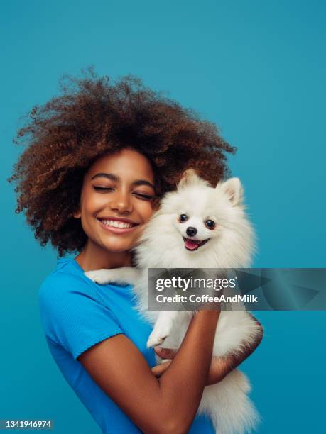 studio portrait of smiling young african american girl  holding little dog - animals and people imagens e fotografias de stock