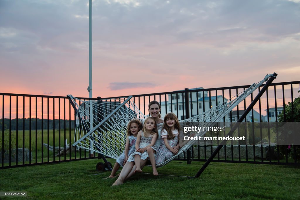 Retrato de noiva madura com filhas na rede ao pôr do sol.