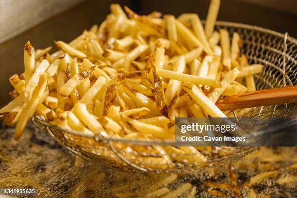 stack of fries in a fryer basket - french fries stock pictures, royalty-free photos & images