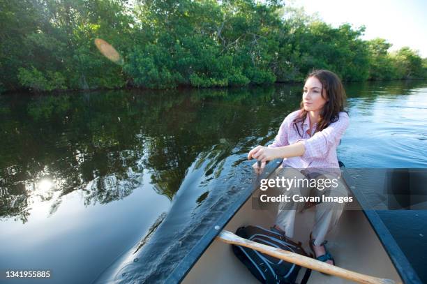 a woman paddles a canoe in everglades national park, florida. - everglades stock-fotos und bilder