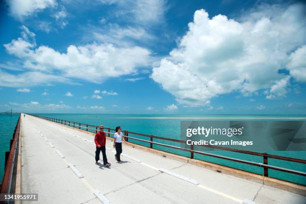 a couple walk along a bridge in florida. - florida bridge stock pictures, royalty-free photos & images