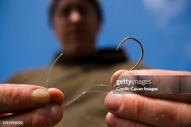 a man ties fishing line to a hook on the lost coast, california. - fishing hook stock-fotos und bilder