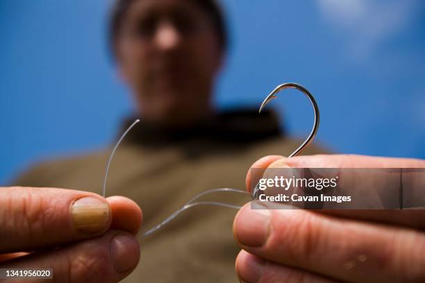 a man ties fishing line to a hook on the lost coast, california. - fishing hook stock pictures, royalty-free photos & images