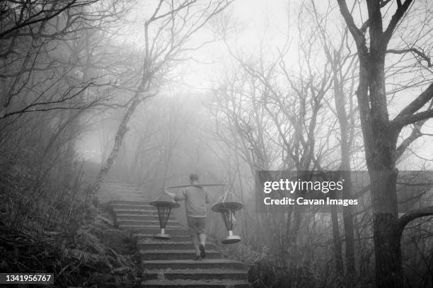 chinese man walking up stairs into fog.  yellow mountain (mt. huangshan), china. - huangshan mountains stock pictures, royalty-free photos & images