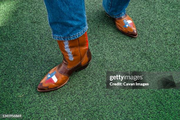 a texan displays his pride of the lone star state with his custom cowboy boots. - texas state flag stock-fotos und bilder