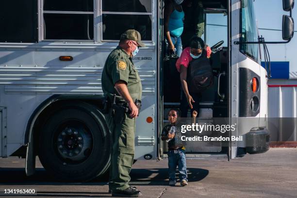 Migrants exit a Border Patrol bus and prepare to be received by the Val Verde Humanitarian Coalition after crossing the Rio Grande on September 22,...
