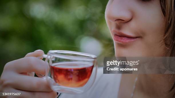 head shot extreme close-up of hispanic young woman drinking a cup of hibiscus hot tea at outdoors terrace - real time stock pictures, royalty-free photos & images