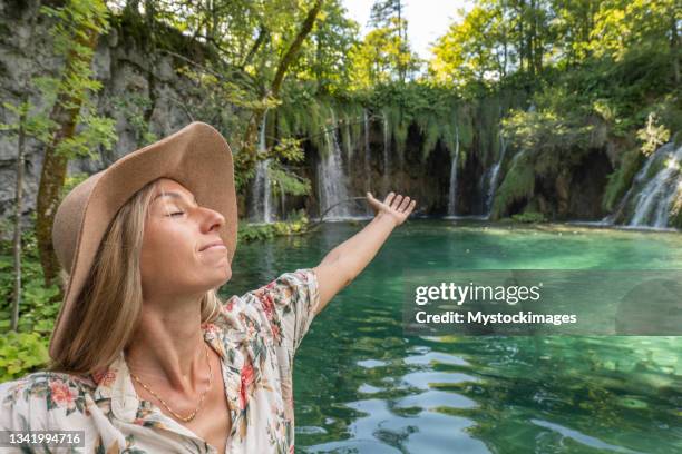 junge frau umarmt die natur, sie steht mit offenen armen in der nähe des sees - plitvice stock-fotos und bilder