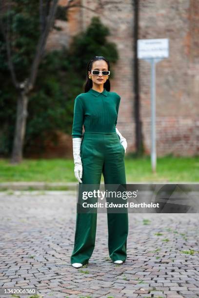 Anna Rosa Vitiello wears white sunglasses, gold large earrings, a dark green long sleeves polo shirt, white leather long gloves, dark green high...