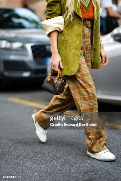 Emili Sindlev wears an orange with yellow and green striped V-neck collar wool pullover, a khaki green ribbed velvet long oversized blazer jacket,...