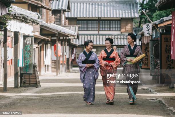 japanische frau, die in der stadt der edo-zeit spazieren geht - historical reenactment stock-fotos und bilder