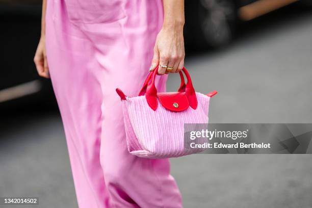 Julia Comil wears a pale pink long midi dress, gold rings, a pale pink velvet with red shiny leather Longchamp handbag, outside the Alberta Ferretti...