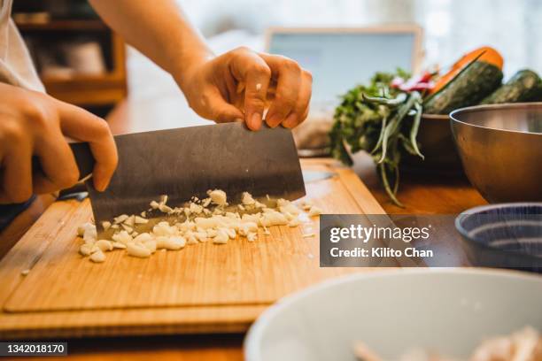 asian woman chopping garlic on the kitchen while learning cooking from digital tablet - chopping vegetables stock pictures, royalty-free photos & images