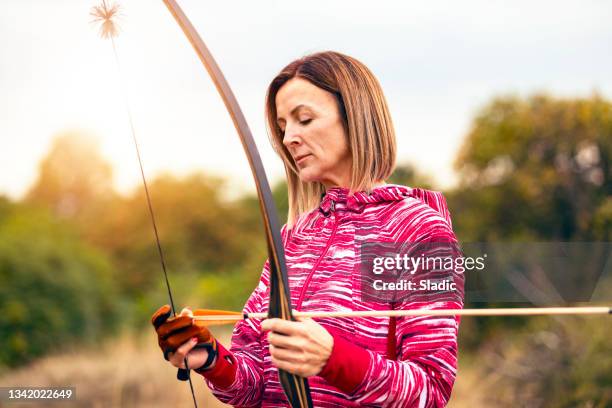a woman on an archery field - arco de arqueiro imagens e fotografias de stock