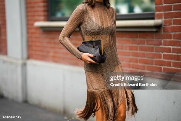 Karina Niguay wears a beige cut-out turtlenekc / long sleeves / fringed knees dress, black underwear, a black shiny leather pattern Fendi puffy...