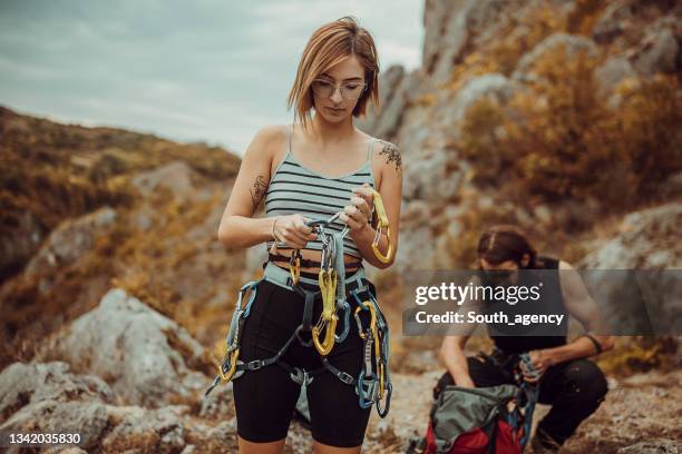 paar legt kletterausrüstung an, bindet knoten für sicherheitsgurte und bereitet sich auf das klettern vor - sicherheitsausrüstung stock-fotos und bilder