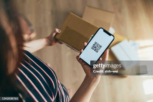 asian woman scanning qr code of parcel - qr code stockfoto's en -beelden