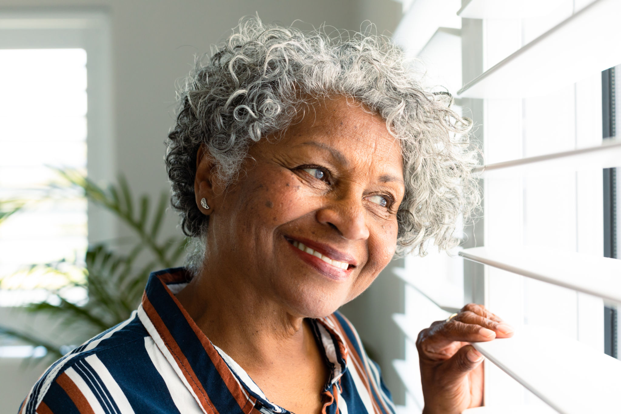 Portrait of smiling african american senior woman looking through window Portrait of smiling african american senior woman looking through window