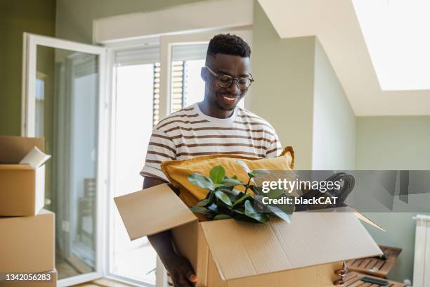 jeune homme emménageant dans un nouvel appartement - déménagement photos et images de collection