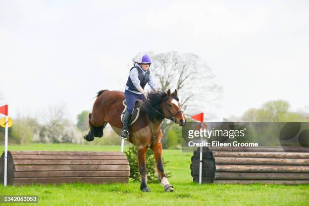 up and over-young rider and her horse enjoying competing in cross country competition in the beautiful shropshire countryside. - bay horse stockfoto's en -beelden
