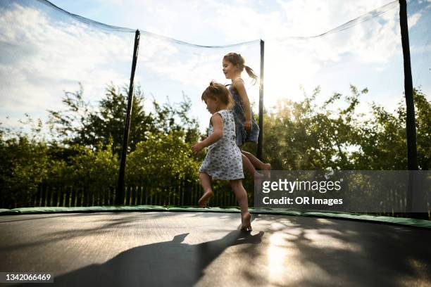 two sisters bouncing on a trampoline - trampoline stock-fotos und bilder