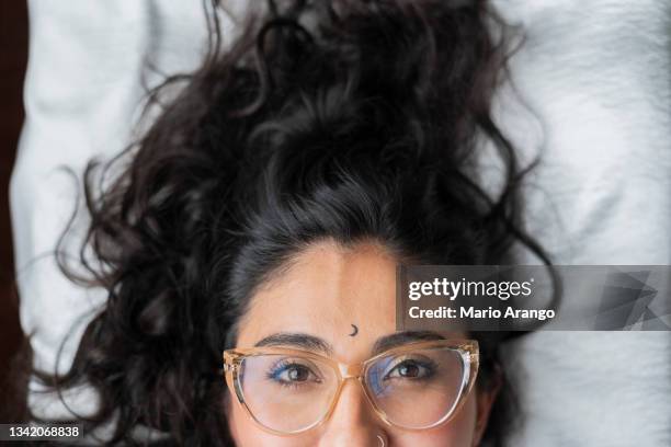 beautiful latin woman from bogotá colombia between 30 and 34 years old, lying down looking at the camera wearing her glasses and disheveled - woman 30 years old portrait stock pictures, royalty-free photos & images