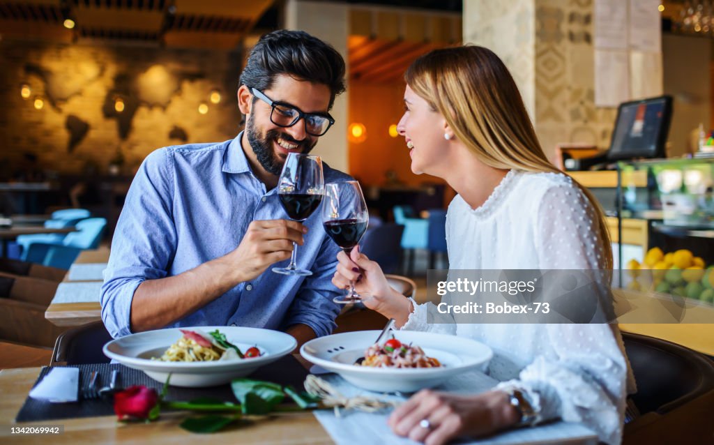 Red wine and paste. Happy couple enjoying lunch in the restaurant. Lifestyle, love, relationships, food concept