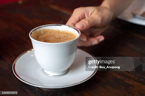 someone hand holding a cup of masala tea on wooden table. - chai tea stockfoto's en -beelden
