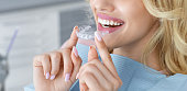 Unrecognizable female patient holding invisible braces or trainer, panorama